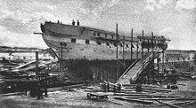 A photograph of a ship out of the water and under repair