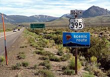 White sign in foreground saying "South US 395" and green sign in background giving distances to June Lake, Mammoth Lakes and Los Angeles.