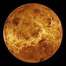 A false color image of Venus. Ribbons of lighter color stretch haphazardly across the surface. Plainer areas of more even colouration lie between.