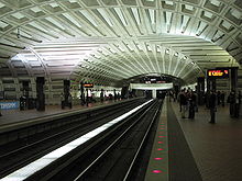 A cement-lined ceiling arches over an underground station. Two lines cross at right angles on separate levels.