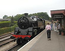 Station platform with black locomotive.