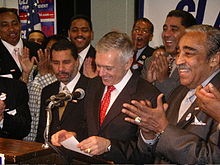 Rangel and General Wesley Clark at a podium, with a number of men standing behind them