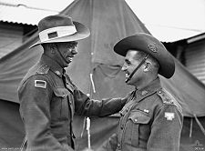 Two smiling men in military uniform shaking hands.