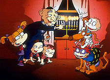 A cartoon of an elderly man lighting a Menorah. He is bald and wearing a Kippah. At his feet are three toddlers; two are on their hands and knees, the other is standing. To their right are two infants sitting on a large dog. One infant is bald and wearing a nappy; the other is wearing a t-shirt and shorts.