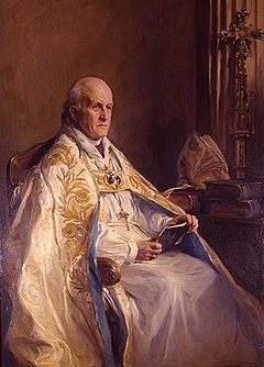 An elderly man with a solemn expression is seated in colourful robes, facing right. He is holding, but not reading, a book.