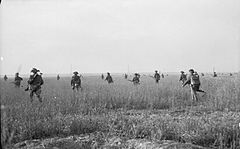 A dispersed group of infantry moving through a field