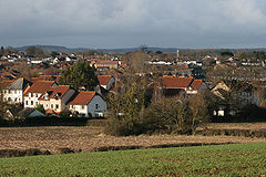 Multiple reddish brown roofs of houses. A church tower is visible in the distance.