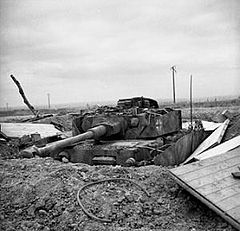 A frontal view of a knocked out German tank in a hull-down position, protected by earth entrenchments.