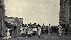  A row of soldiers, left, aim their rifles at a lone figure, right, while (centre) an officer raises his sword as a signal. An agitated woman, extreme left, turns her face from the scene.