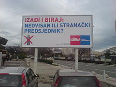Pro-Bandić billboard in parking lot, with blue and red letters on white background