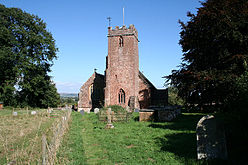 Reddish stone building with square tower.