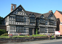A highly detailed black-and-white timber-framed house with four gables