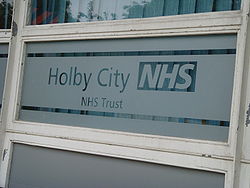 A partially frosted window which reads 'Holby City NHS, NHS Trust'