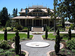 A gravel walkway lined with plants leads to a stately two-story home with a large porch.