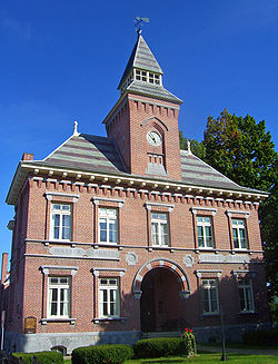 Front view of old courthouse building, with a brick clock tower and pointed slate roof