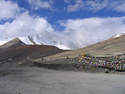 Gravel road through high mountains with brightly colored flags at the side