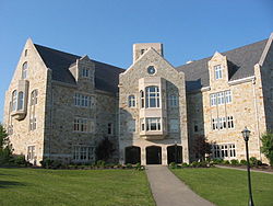 A 4 story stone building, with an asphalt walkway leading to a large entrance area