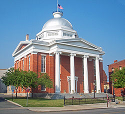 A brick building with four white columns in front and a silvery dome on top