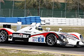 Side view of #6 white sports racing car with the words Muscle Milk on the side