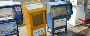 Empty newspaper vending boxes on the street, left to right, the Los Angeles Times (cut off), Epoch Times, a San Diego paper (Gone to the Web, sddt.com), a white unnamed box, and the San Diego Business Journal (cut off)