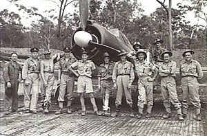 Twelve men wearing military uniforms standing in front of a single-engined World War II-era propeller fighter aircraft
