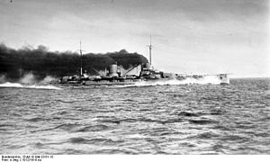 A large gray warship steams at full speed; thick black smoke pours from its two funnels.