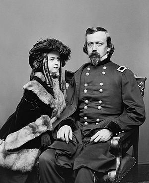 Full body shot of Charles P. Stone in his military uniform, sitting in a chair with his daughter at his side. The image is in black and white
