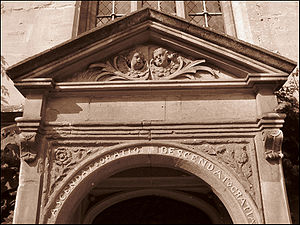Part of a stone doorway.  The top is triangular, with the heads of two cherubs in the panel beneath. On the curved arch immediately above the entrance, the words "Ascendat oratio descendat Gratia"; a rose and a thistle on the adjoining panels
