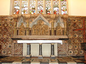 A marble reredos beneath a stained glass window, with three scenes from the Crucifixion; a granite altar with six pillars
