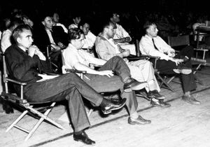 A group of men in shirtsleeves sitting on folding chairs.