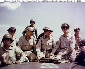 Eight men in khaki uniforms, seated.