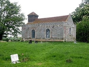A small simple rectangular brick church seen from the southeast with two round-headed windows on the south side and a bellcote on the west gable
