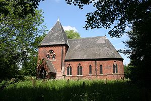 A red brick church seeen from the southeast with a squat loww tower and porch on the left, and a chancel with an apse on the right