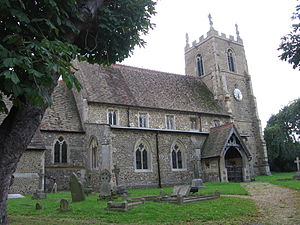 A stone church seen from the northeast showing part of the chancel, the nave with clerestory, a north porch, and an embattled tower with a statue on the top of each corner