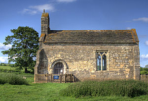 A small chapel seen from the south, with a bellcote at the left, a door and a single window
