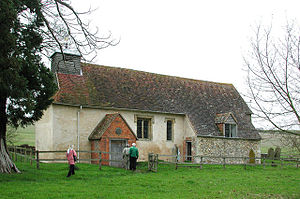 A small simple church, largely rendered with a tiled roof, a brick porch, and a bellcote at the west end