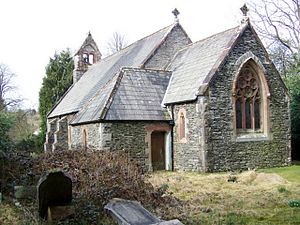 A small stone church seen from the southeast with a short chancel, a porch at the southeast, a buttressed nave, and a west bellcote