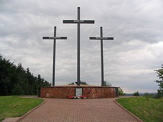 A Memorial consisting of three crosses standing on a large brick pedestal. Each cross bears a name - Katyn, Kharkiv, or Mednoye.