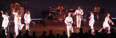 The performers on Byrne's tour wear all-white jumpsuits while dancing, playing their instruments, and singing.