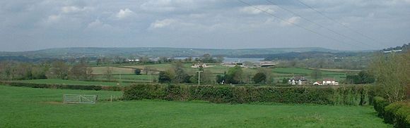 View of Chew Valley Lake in the distance with green farmland in the foreground and hills in the distance