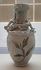 A tall, thin, off white vase with an eastern dragon wrapped around the portion where the main body of the vase and the beginning of the rim area meet.